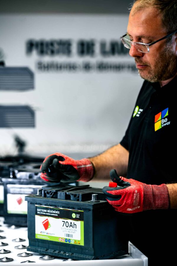Technicien qualifié régénérant une batterie de démarrage automobile dans un centre spécialisé en reconditionnement de batteries, utilisant des équipements professionnels pour restaurer performance et durée de vie.